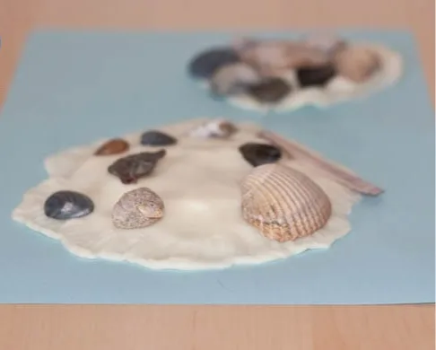 Kinderen knutselen met schelpen op blauw papier als zomers knutselidee