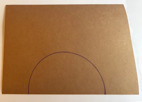 Een halve cirkel getekend op bruin papier als begin van het knutselen van een ijsje van papier