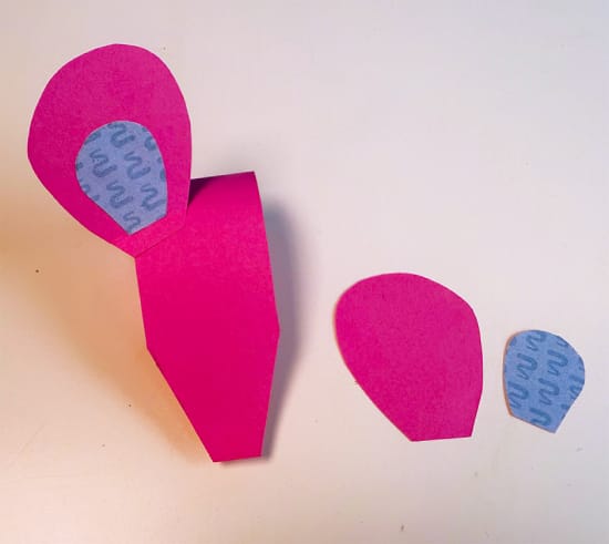 Eén oor op het hoofd van een muis van papier geplakt, tweede oor ligt klaar