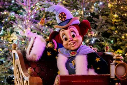Pardoes in de Winter Efteling, zwaait vanuit een slee voor een kerstboom met lichtjes.