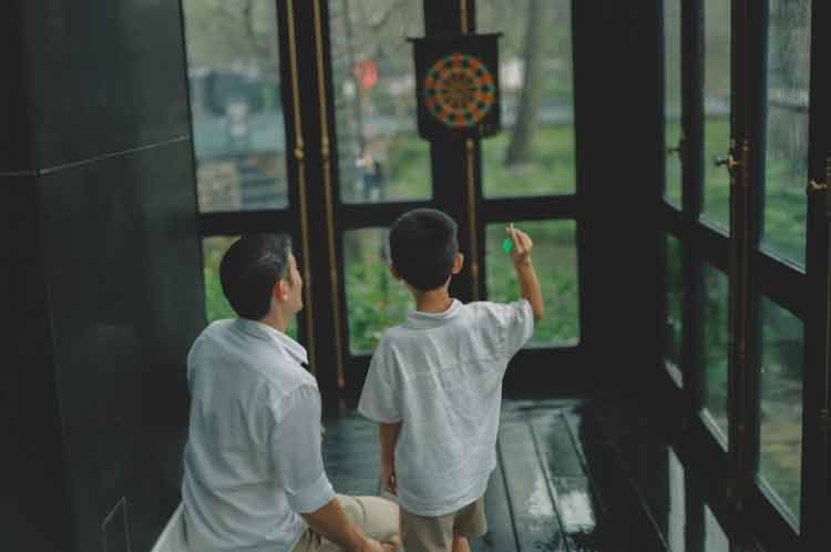Ouder en kind spelen binnen darts bij de deur.