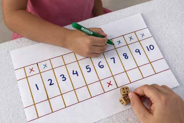 Kind oefent rekenen thuis met shut the box werkblad en dobbelstenen