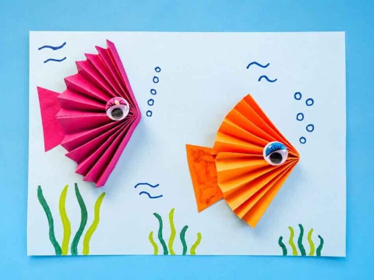Twee visjes van gevouwen papier op een onderwaterachtergrond met zeewier en bubbels
