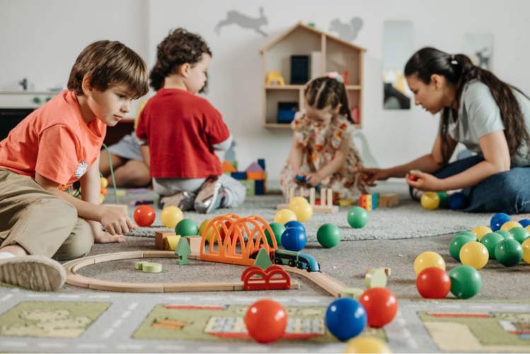 Kinderen spelen samen met een pedagogisch medewerker op een kinderdagverblijf